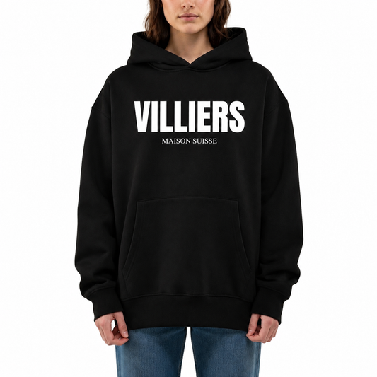 Damen Oversize Hoodie von VILLIERS MAISON SUISSE in Schwarz mit weissem Logo auf der Brust, getragen von einem Model in Frontansicht.