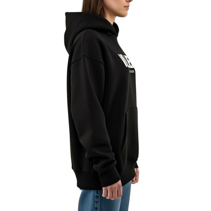 Damen Oversize Hoodie von VILLIERS MAISON SUISSE in Schwarz mit weissem Brustlogo, getragen von einem Model in seitlicher Ansicht.