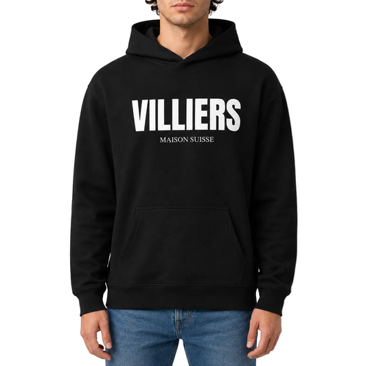 Herren Oversize Hoodie von VILLIERS MAISON SUISSE in Schwarz mit weißem Logo auf der Brust, getragen von einem Model in der Frontansicht.