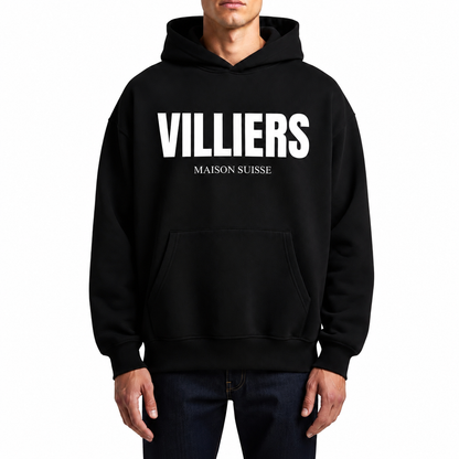 Herren Oversize Hoodie von VILLIERS MAISON SUISSE in Schwarz mit weissem Logo auf der Brust, getragen von einem Model in Frontansicht.