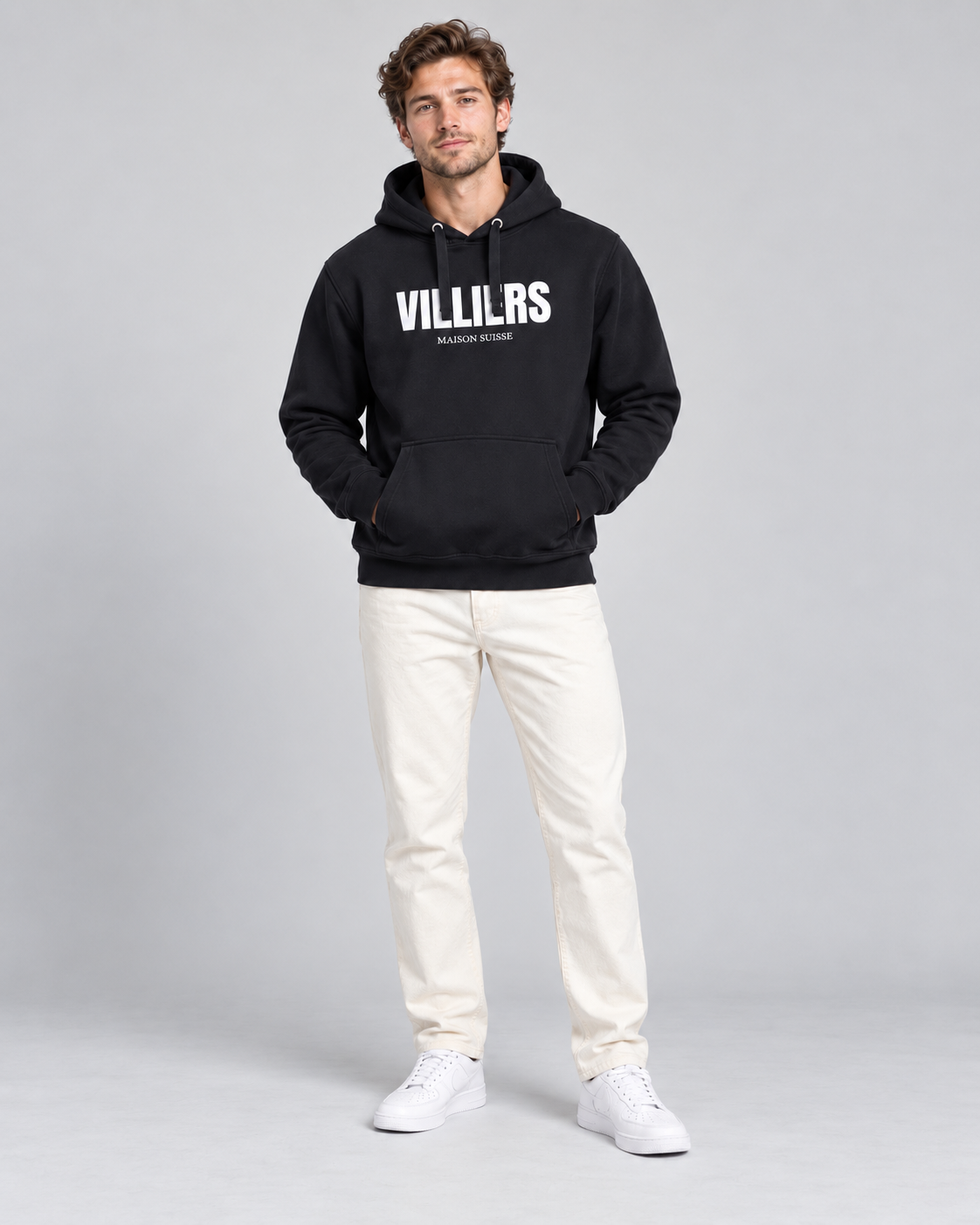 Mann trägt schwarzen Premium Hoodie von Villiers Maison Suisse zu cremefarbener Hose, Ganzkörper von vorne
