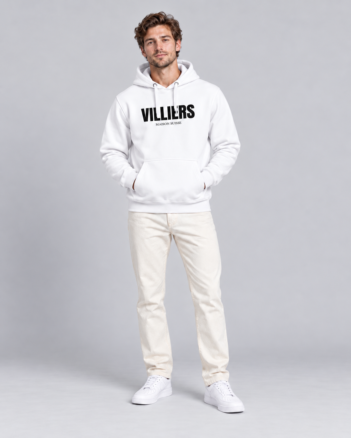 Mann trägt weissen Premium Hoodie von Villiers Maison Suisse zu cremefarbener Hose, Ganzkörper von vorne