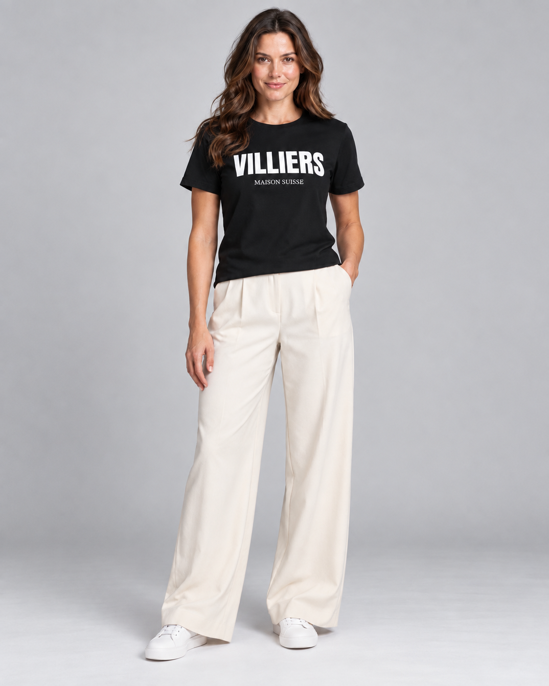 Frau trägt schwarzes T-Shirt von Villiers Maison Suisse zu cremefarbener Hose, Ganzkörper von vorne
