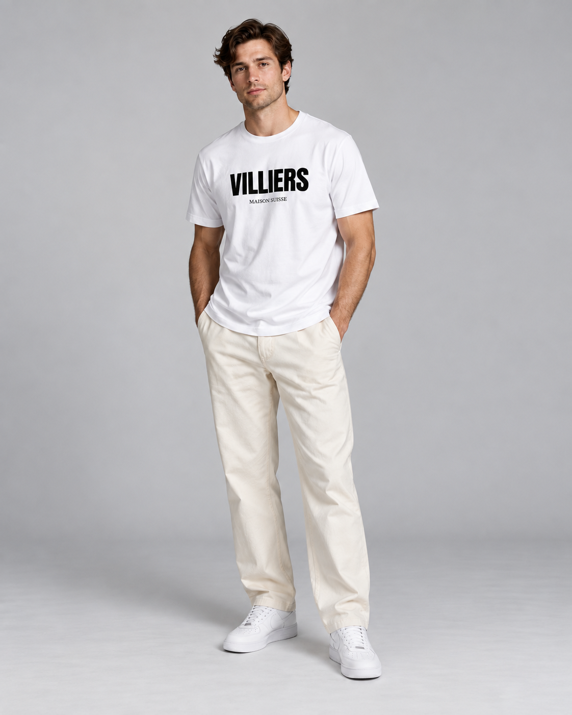 Mann trägt weisses T-Shirt von Villiers Maison Suisse zu cremefarbener Hose, Ganzkörper von vorne
